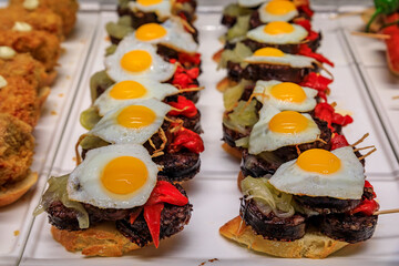 Spanish pintxos of morcilla blood sausage with egg and piquillo peppers on display in a restaurant,...