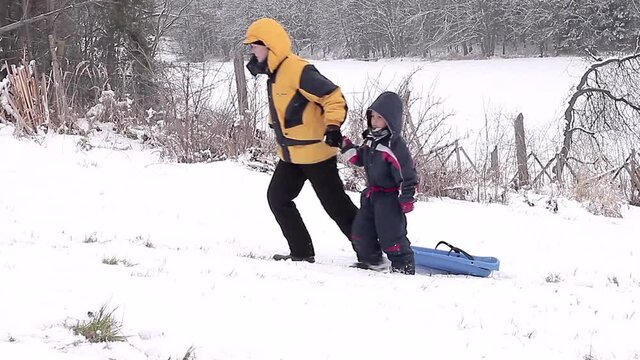 mother and child on sledge in the snow having a great time going up hill stock video