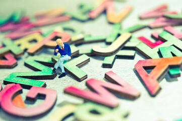 miniature figurine sitting on alphabet letters, teaching language concept