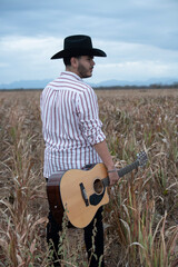 JOVEN MEXICANO LATINO CON BARBA TOCA LA GUITARRA 