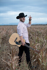 JOVEN MEXICANO LATINO CON BARBA TOCA LA GUITARRA 