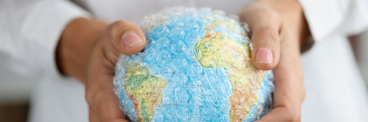 Woman holds plastic covered globe showing environmental problems