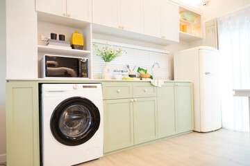 Modern green kitchen interior with washing machine and microwave.