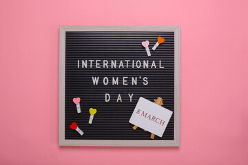 Creative Flat lay out of international women's day with mini hearts on clothespins and signboard saying 8 march on pink background