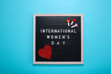 Flat lay of international women's day inscription framed with sparkling red heart and mini heart on clothespin