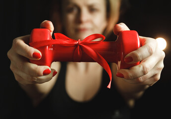 Young girl holding a small red dumbbell with ribbon as a gift for Valentine's Day, birthday, anniversary or wedding.