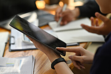 Cropped image of young office workers working together with a digital tablet and computer laptop at...