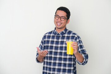 Adult Asian man smiling happy while presenting a cup of fresh yellow juice drink