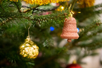 Fototapeta premium Closeup of Festively Decorated Christmas tree with beautiful toys on blurred fir fairy background. Defocused garland lights, Bokeh effect. Christmas background - baubles and branch of spruce tree.