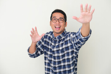 Adult Asian man showing excited expression when trying to grab something that fall from above