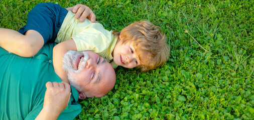 Happy grandfather and grandson relaxing together on grass. Child with Grandfather dreams in summer...
