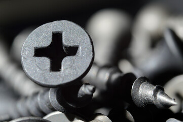 black hardened self-tapping screws lies on a dark background. close-up.