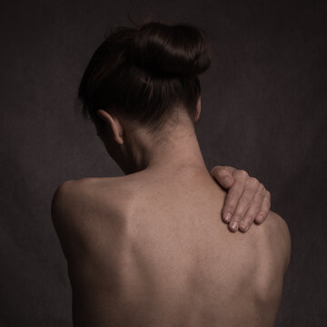 Fine art studio portrait of back of lonely naked woman with hand 