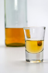 Alcoholic drink in a glass and bottle of brandy in the back on white table. Of strong alcoholic intoxication. The concept of alcohol dependence. Alcohol intoxication.