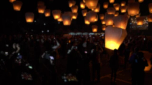 Defocused shot of many asian fire lanterns launching during buddhist festival in chinese new year in Taipei. Rice paper hot air balloons floating in traditional flying sky lantern celebration