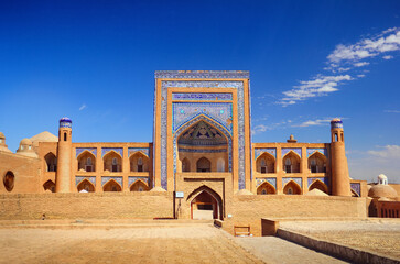 Beautiful old city, ancient Allakuli Khan Madrassah (Allah Quli Madrasa), at the background of bright blue sky in Historic Center of Khiva (UNESCO World Heritage Site), Uzbekistan, Central Asia