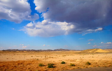 Photo from a moving car - beautiful scenery of colorful sand, dunes and rare plants against the background of blue sky in Kyzyl Kum (Kyzylkum, Qyzylqum, Qizilqum) desert, Uzbekistan, Central Asia