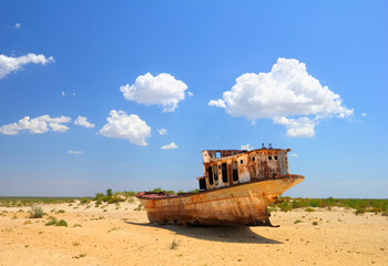 Desert scenic view of a dryied Aral Sea with old abandoned boat against the background of bright blue sky around Moynaq, (Muynak or Moynoq), Uzbekistan, Central Asia