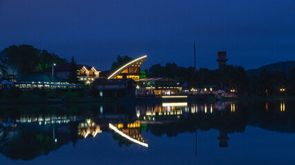 Burning lights of night establishments near the lake. Lake view and burning lights in buildings at night. Reflection of lights in the lake