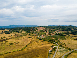 Casale Marittimo, Tuscany, Pisa region, Medieval old town with cypress tress and crops hay, city on a hill top, landscape drone aerial panorama	