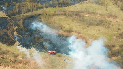 Fototapeta premium 4K Aerial View Spring Dry Grass Burns During Drought Hot Weather. Bush Fire And Smoke. Fire Engine, Fire Truck On Firefighting Operation. Wild Open Fire Destroys Grass. Ecological Problem Air