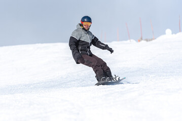 Fototapeta na wymiar Young man snowboarding on the slopes of a ski resort.