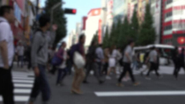 Blurred defocused view of crowd of people crossing the street at Tokyo Akihabara area, known for electronic and anime stores in Japan. Asian pedestrian crosswalk. Japanese shopping