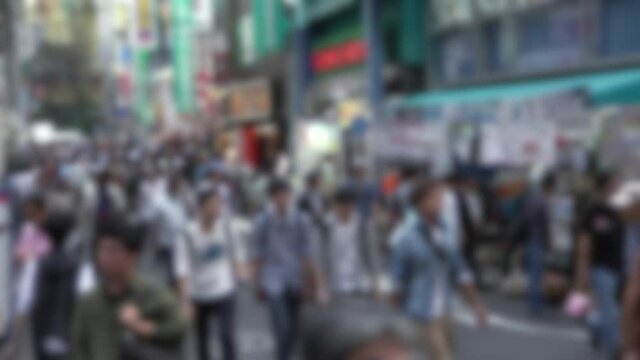 Defocused shot of crowd of people walking in the street at Tokyo Akihabara area, known for electronic and anime stores in Japan. Asian pedestrian shopping in Japanese shops. Blurred background