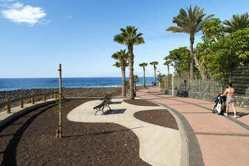 Tourists stroll along the promenade along the coastline in La Caleta, Costa Adeje, Tenerife