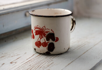 Old enamel mug on the windowsill