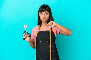 Young mixed race seasmtress woman isolated on blue background showing thumb down with negative...