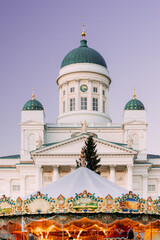 Helsinki, Finland. Xmas Market On Senate Square With Holiday Carousel And Famous Landmark Is Lutheran Cathedral And Monument To Russian Emperor Alexander II At Evening