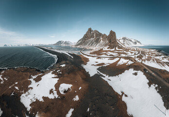 Aerial Drone panorama view of a snow covered Eystrahorn mountain in Iceland at Hvalnes peninsula with black sand beach. - Powered by Adobe