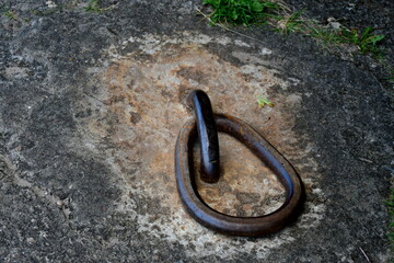 A close up on a metal hinge or chain fragment being a part of a concrete entrance to a bunker or bomb shelter located in the middle of a dense forest or moor seen on a sunny summer day in Poland