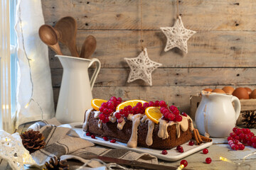 Traditional christmas cinnamon cake decorated with fruits and spekulatius cookies cream on a kitchen countertop.