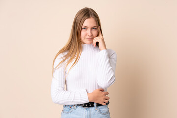 Teenager Ukrainian girl isolated on beige background thinking an idea