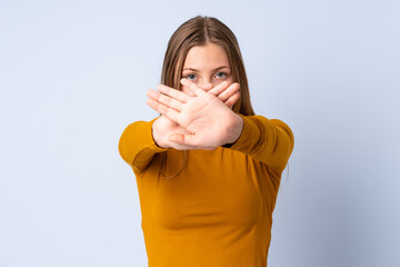 Teenager Ukrainian girl isolated on blue background making stop gesture with her hand to stop an act