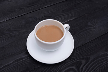Top view of white cup of creamy coffee on black wooden table