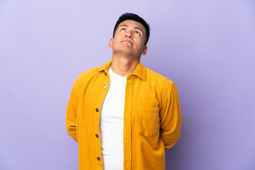 Fototapeta premium Young Ecuadorian man isolated on purple background and looking up