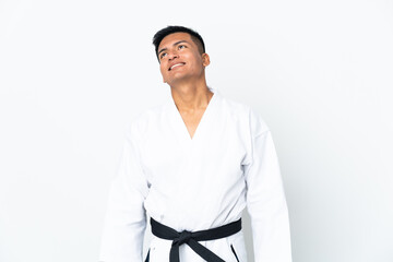 Young Ecuadorian man doing karate isolated on white background thinking an idea while looking up