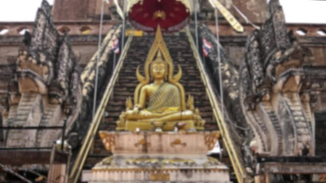Defocused shot of a golden Buddha statue, eighteen-cube Buddha. A Buddhist temple in the historical center of Chiang Mai. Blurred background in the scene