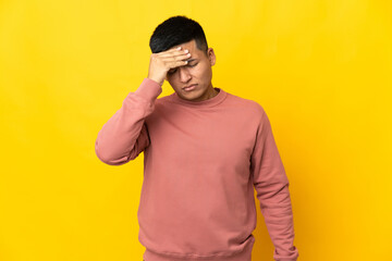 Young Ecuadorian man isolated on yellow background with headache