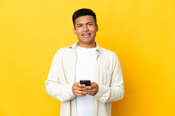 Young Ecuadorian man isolated on yellow background surprised and sending a message