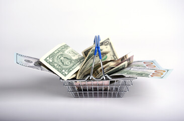 US dollar bills in cash in a mini supermarket basket on a white background