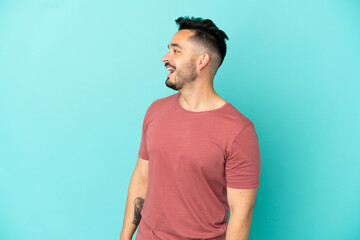 Young caucasian man isolated on blue background laughing in lateral position