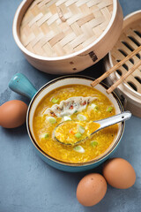 Chinese egg-drop soup served with steamed dumpling and scallions, elevated view on a grey concrete background, vertical shot