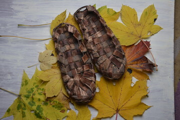 Birchen woven bast shoes hang on a log wall.
