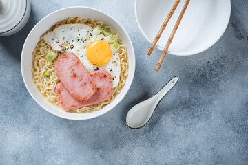 White bowl with Hong Kong breakfast or Gong Zai Mein, above view on a light-blue stone background, horizontal shot