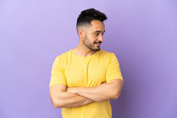 Young caucasian man isolated on purple background looking to the side and smiling