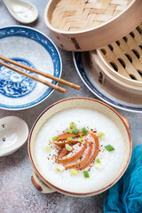 Bowl of asian congee with chicken meat, vertical shot on a roseate metal background, elevated view